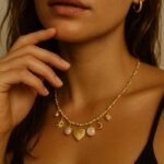 Personne portant un collier pendentifs soleil, cœur, lune, perles et créoles en or.